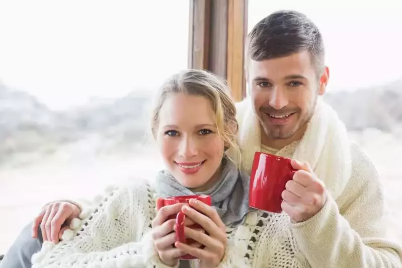 Happy couple in winter sweaters sitting by the window at one of our cabin rentals near Gatlinburg Tennessee.