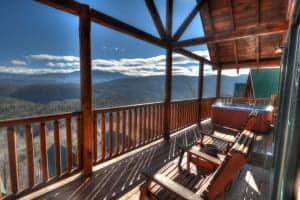 Chairs and a hot tub on the deck of one of our cabin rentals with mountain views.
