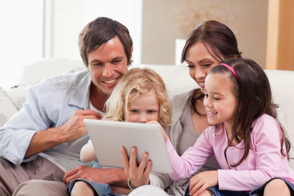 Family using a tablet together on the couch.
