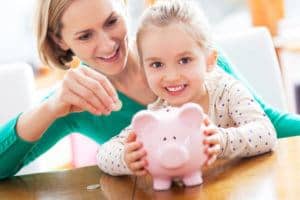 mother and daughter putting money in piggy bank