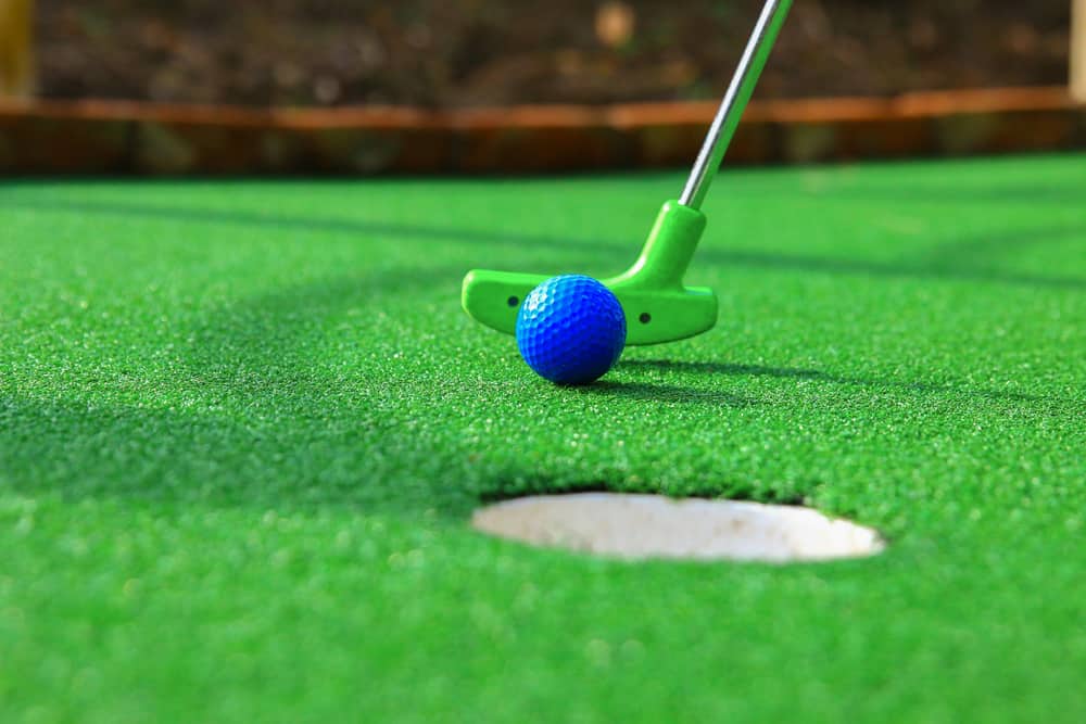 blue golf ball being putted into hole